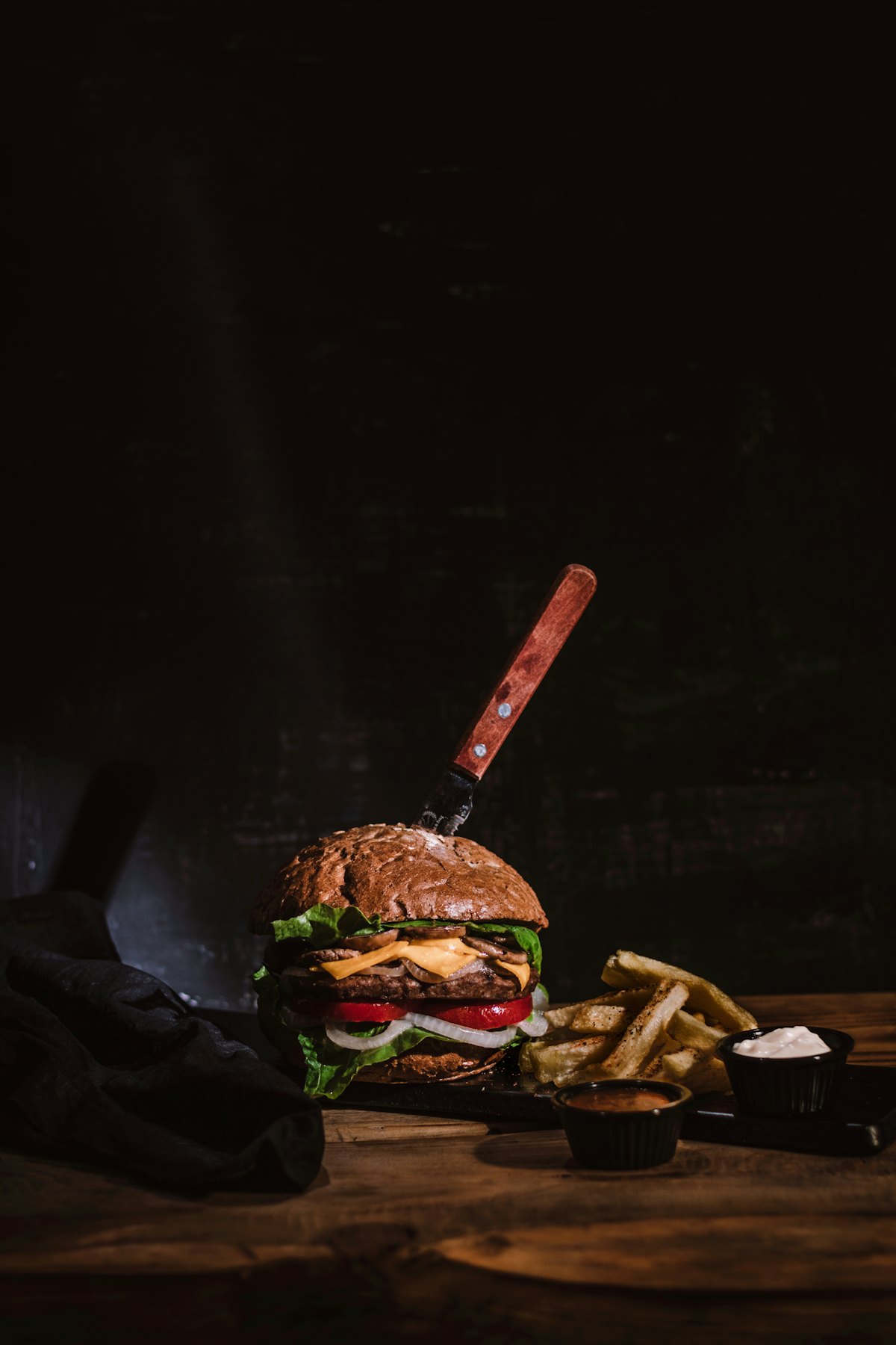 A stacked burger with chips and sauces